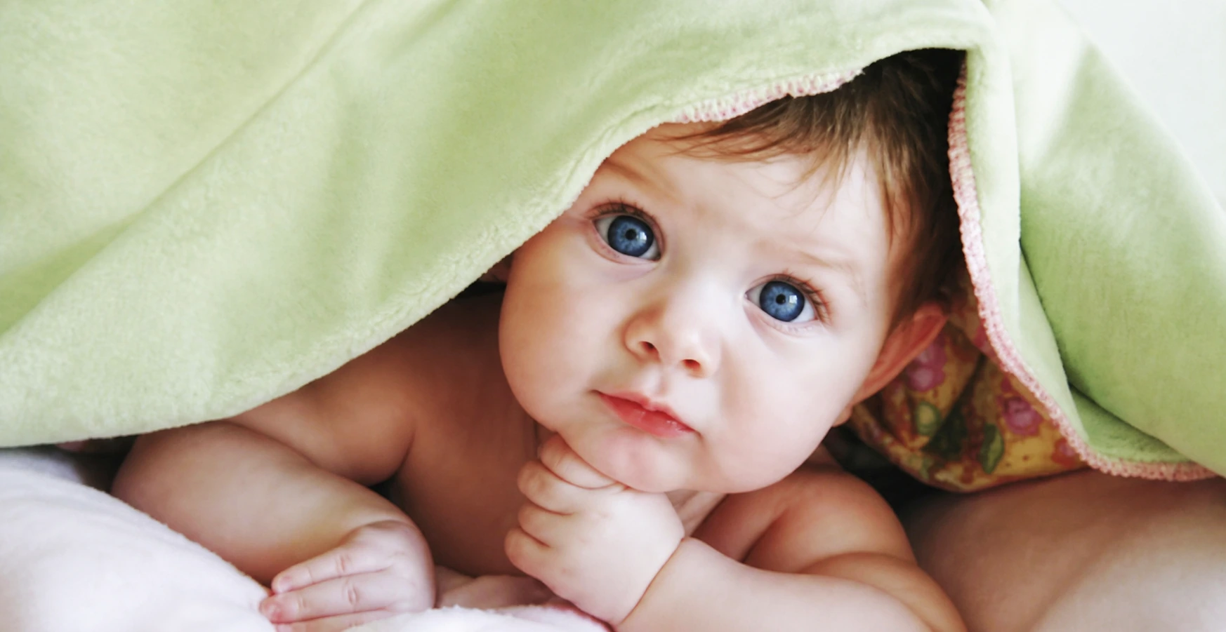 Baby resting under a pale green blanket